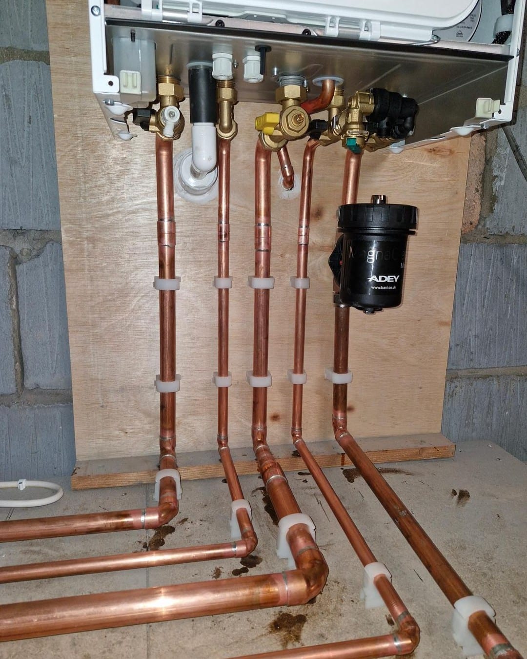 Straight copper pipework and a magnetic filter set out on a plywood backboard