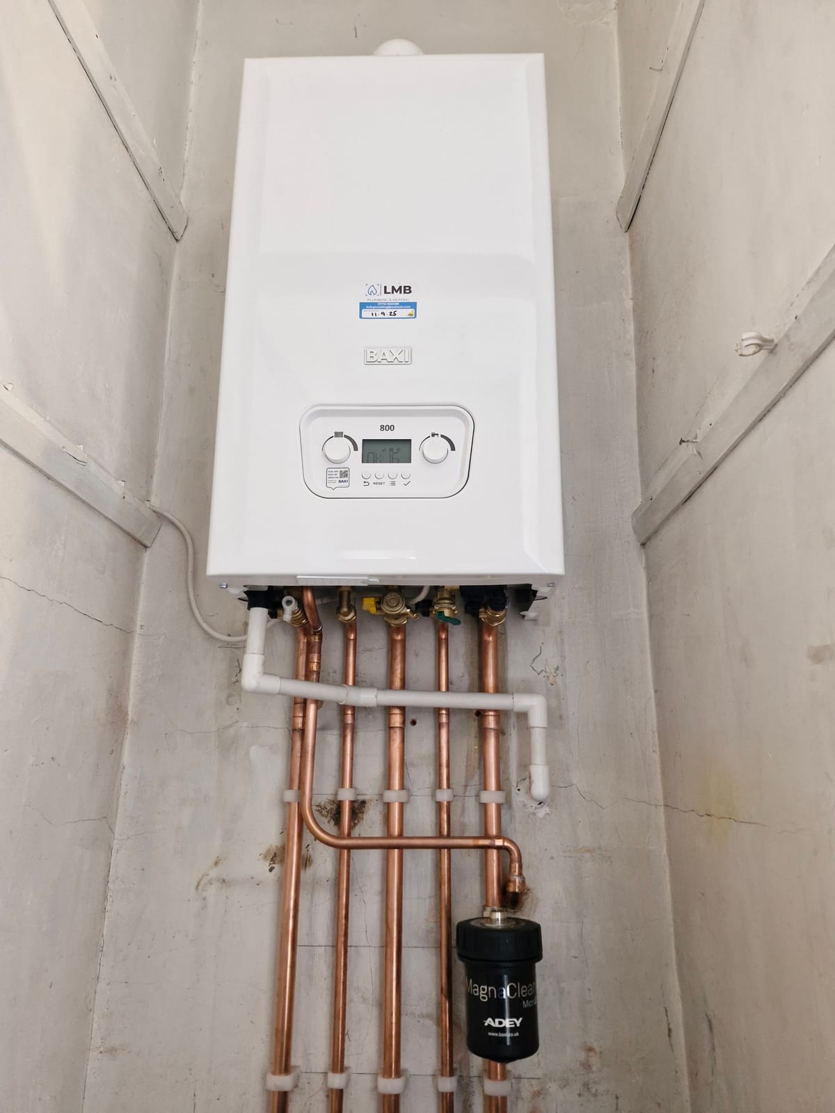 A newly fitted boiler in a cupboard with copper pipework and a magnetic filter, from the team doing oil boiler installation in Pontyclun
