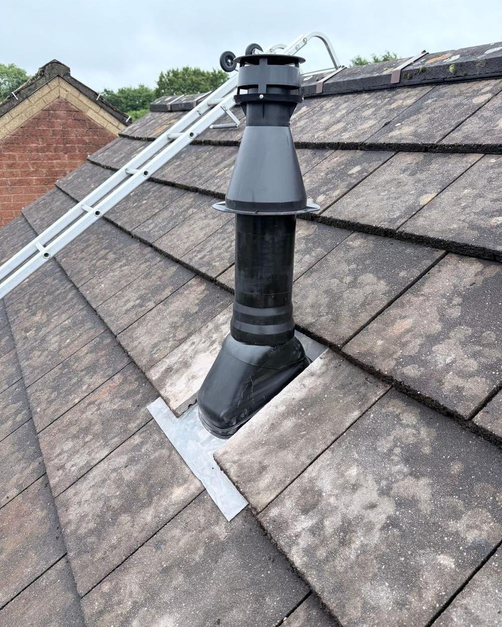A new boiler flue through a tiled roof, with trees behind, on one of our recent jobs, by the team behind Oil Boiler Installation Bridgend